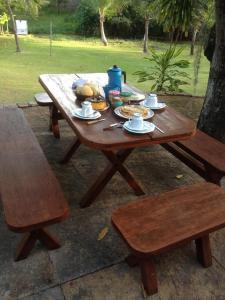 una mesa de picnic de madera con platos de comida. en Toca do Jacaré, en Granja Beira Mar