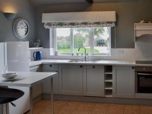 a white kitchen with a sink and a window at Oxley Cottage in Orby