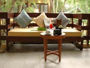 Un banco con almohadas y una mesa auxiliar. en Baan Talay Dao Resort, en Hua Hin