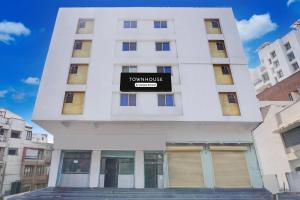 a white building with a sign on it at Townhouse Ambegaon Road Katraj Formerly White Castle in Pune