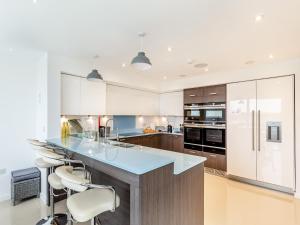 a kitchen with white cabinets and a blue counter top at Seascape in Polruan