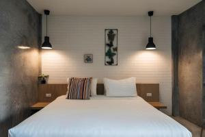 a large white bed in a room with two lights at Journey Hostel Surat in Ban Tha Kup
