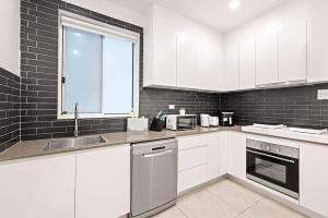 a kitchen with white cabinets and a sink and a window at Cozy Double Room in Kensington - Walk to UNSW Easy CBD Access -External and Shared Kitchen or Bathroom Access in Sydney