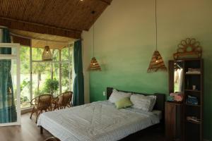 a bedroom with a bed and a green wall at Rosee de Kala - Golden Buurin in Di Linh