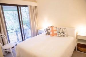 a bedroom with a white bed and a balcony at The Sandy Shack in Sandy Point