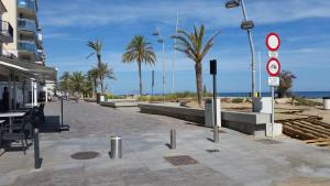 a sidewalk next to a beach with palm trees and a building at Apartamento Calafell playa in Calafell