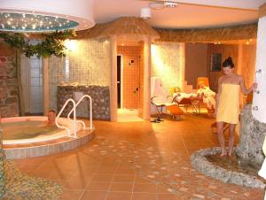 a woman standing next to a jacuzzi tub in a room at Scharfegger's Raxalpenhof - Zuhause am Land in Reichenau