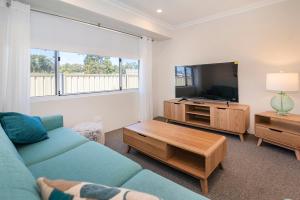 a living room with a blue couch and a tv at Dunsborough Sunrise in Dunsborough