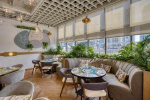 a restaurant with couches and tables and plants at Millennium Place Marina in Dubai