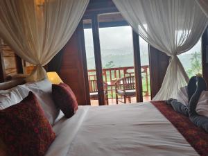 a bedroom with a bed with a view of a balcony at Bukit Luah Sidemen in Sidemen