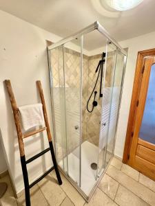 a shower with a glass enclosure next to a chair at Trullo Sabotino in Alberobello +4 photos