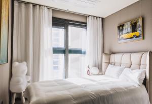 a bedroom with a white bed and a window at Vourne Osiria in Busan
