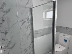 a bathroom with a toilet and a glass shower at Footscray Motor Inn and Serviced Apartments in Melbourne +21 photos
