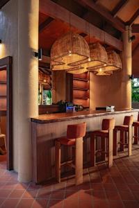a kitchen with a bar with chairs and pendant lights at Kira Baya Koh Samed in Ko Samed