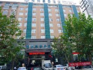 un grand bâtiment avec des voitures garées devant dans l'établissement GreenTree Inn Henan Shangqiu Yongcheng Ouya Road Business Hotel, à Houling