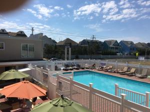 a swimming pool with chairs and umbrellas on a balcony at Dunes by the Ocean in Point Pleasant Beach