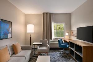 a living room with a couch and a desk and a television at Candlewood Suites Springfield By IHG in Southlawn