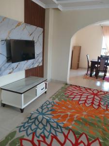 ein Wohnzimmer mit Flachbildfernseher und Tisch in der Unterkunft Muna's Home in Isiolo