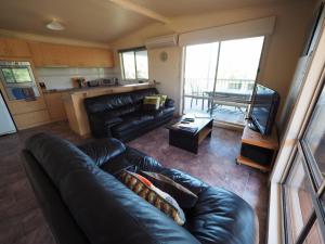 a living room with a leather couch and a television at Sunset Deck Stay 3 Pay 2 Winter Special in Sandy Point