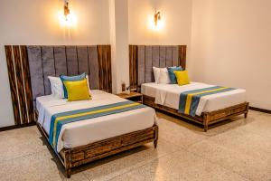 two beds with colorful pillows in a room at Nethra Beach in Hikkaduwa