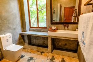 a bathroom with a toilet and a sink and a window at Nethra Beach in Hikkaduwa