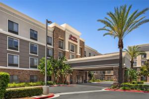 莫雷诺谷Hampton Inn & Suites Moreno Valley的公寓大楼前方有棕榈树