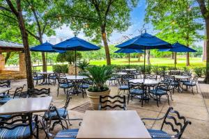 an outdoor patio with tables and chairs with blue umbrellas at Hilton DFW Lakes Executive Conference Center in Grapevine