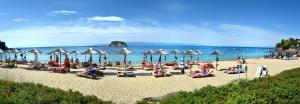 a group of people sitting on a beach with umbrellas at Hotel Korali in Troulos