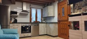 eine Küche mit Holzschränken und einem blauen Sofa in der Unterkunft EL PICO Casa en plena naturaleza con vistas espectaculares in Arredondo + 18 Fotos