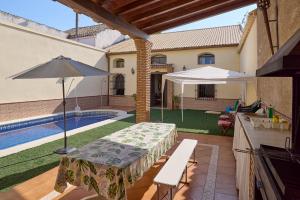 a patio with a table and an umbrella and a pool at Vivienda Turística Rural Santa Fe in Montilla