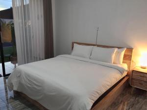 un lit avec des draps blancs et des oreillers dans une chambre dans l'établissement Kayla Homestay, à Nusa Dua