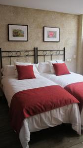 una camera con due letti con lenzuola rosse e bianche di SueñoRural a San Miguel de Valero
