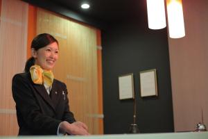 a woman in a suit and a yellow bow tie at Spa Hotel Alpina Hida Takayama in Takayama