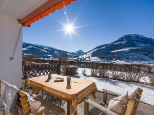 a wooden table and chairs on a patio with snow covered mountains at Apartment Sunnyside Premium by Alpine Host Helpers in Kirchberg in Tirol