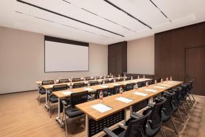 苏州苏州工业园区独墅湖戴斯温德姆酒店的一间会议室,配有桌椅和白色屏幕