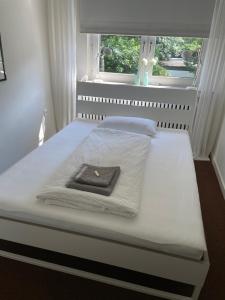 a white bed with a towel on it with a window at Messewohnung Düsseldorf in Düsseldorf