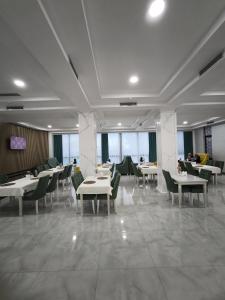 a restaurant with white tables and green chairs at Saroy Gardens Hotel in Fergana +23 photos