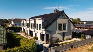 a white house with a black roof at Apartamenty Kormoran in Sarbinowo