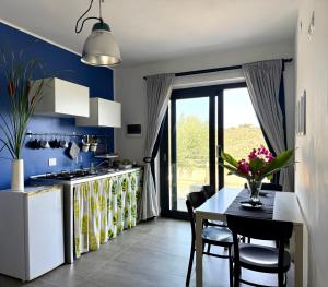 a kitchen with a table and a kitchen with blue walls at La Casa del Riccio in Tindari