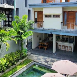 a house with a swimming pool and a patio with an umbrella at Olivia Guest House Canggu in Canggu