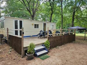 a tiny caravan with a deck and a table and chairs at Le calme in Braize