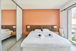 a bedroom with a large white bed with two mirrors at La tranquilité bleue - Maison avec Parking cloturé in Les Sables-dʼOlonne