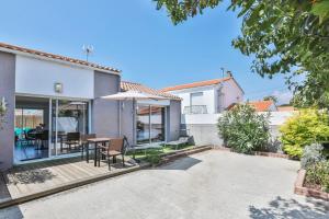 a patio with a table and chairs in a house at La tranquilité bleue - Maison avec Parking cloturé in Les Sables-dʼOlonne