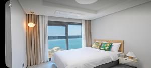 a bedroom with a bed and a large window at 오시리아 해운대 in Busan