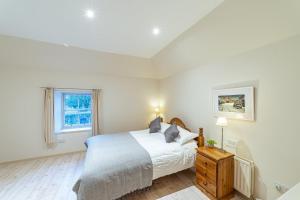 a white bedroom with a bed and a window at Penninghame Estate - Bruce Apartment in Challoch