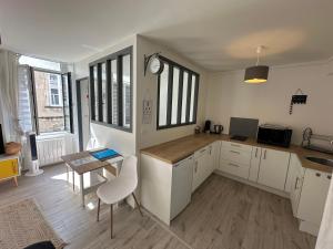 a kitchen with white cabinets and a table and chairs at L'Oasis Marin meublé, lumineux et cosy à 1min à pied du marché dans l'hyper centre de La Rochelle avec TV et Wifi in La Rochelle