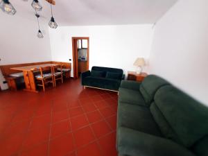 a living room with a green couch and a table at Ca Blanca Rooms in Marsiai