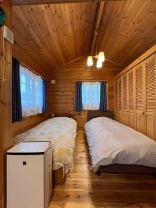 1 Schlafzimmer mit 2 Betten in einer Holzhütte in der Unterkunft コテージコッタロ in Gojikkoku