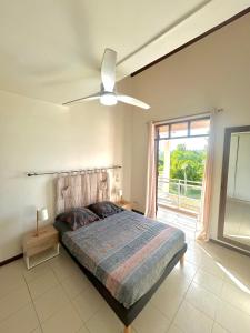 a bedroom with a bed and a ceiling fan at Magnifique Villa avec terrasse et jardin XXL in Sainte-Anne
