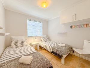 a bedroom with two beds and a desk and a window at Kloof Gardens: Pool Braai with Lagoon Views in Knysna +34 photos